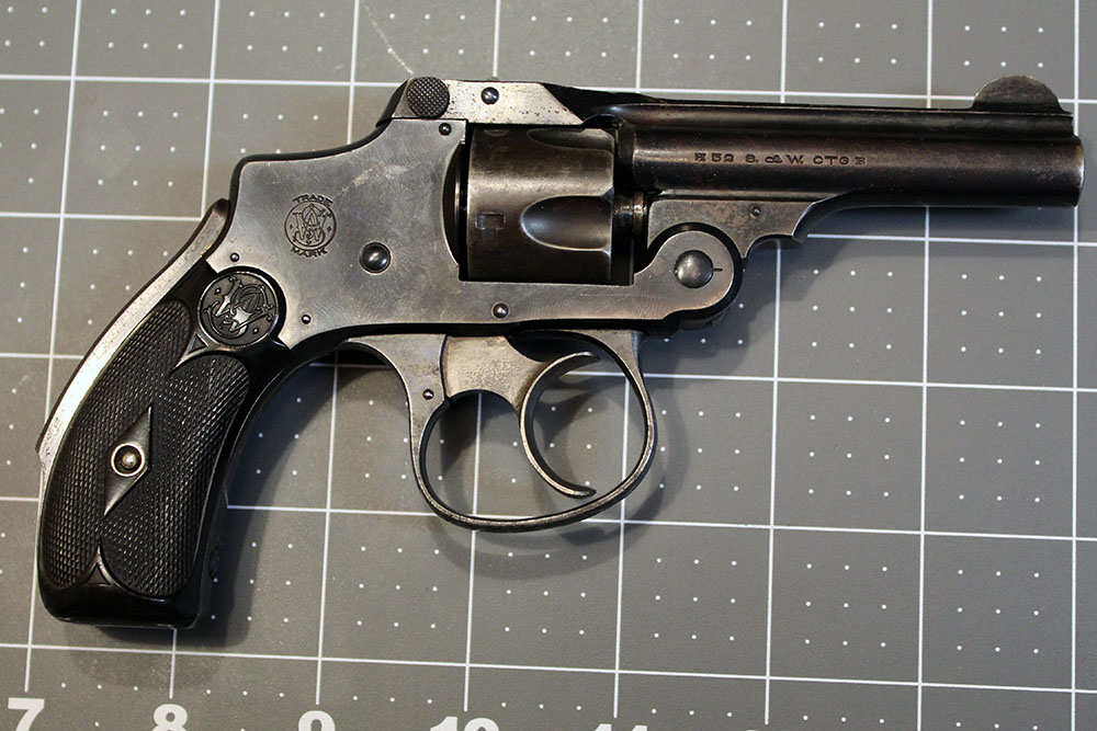 right side view of a Smith & Wesson .32 Safety Hammerless, lying on a gridded crafting mat